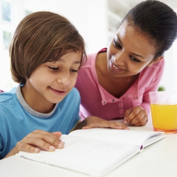 young boy doing homework with help of his mother